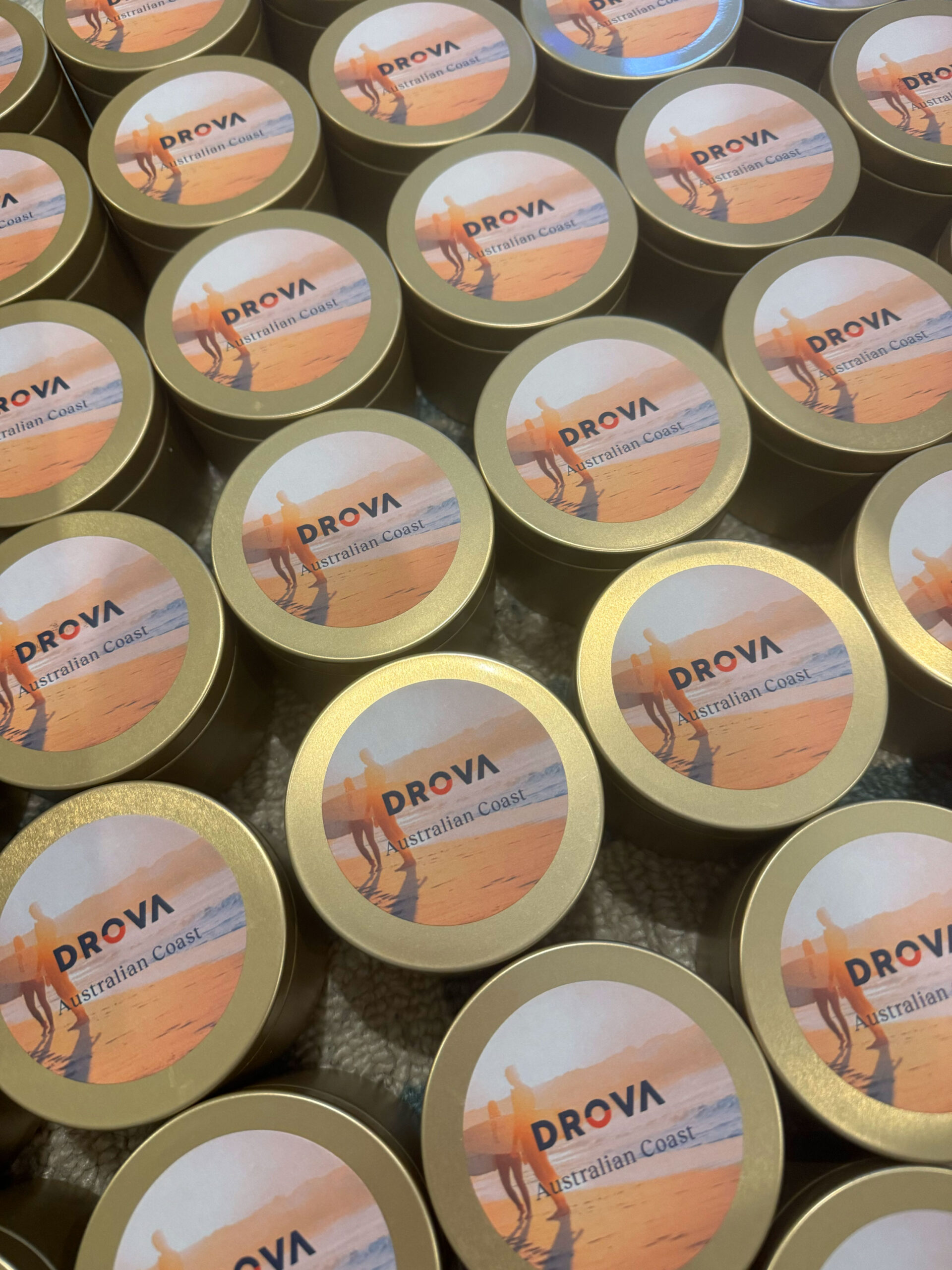 Rows of custom branded soy candle tins with Drova logo labelling for a corporate gifting order